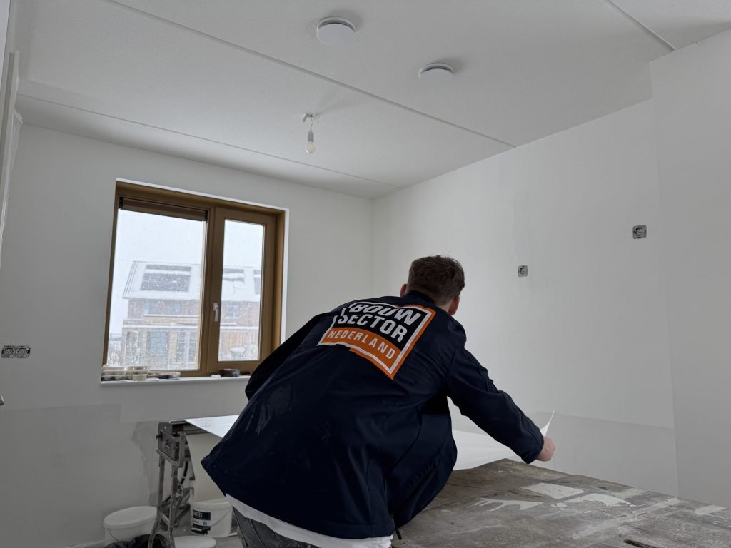Behanger van Bouwsector Nederland werkt aan een baan op de plaktafel in een lege kamer