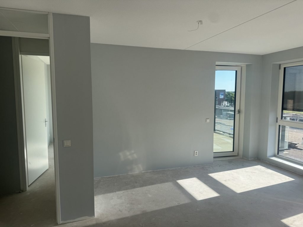 Lege nieuwbouwkamer met kale, vlakke wanden en een betonvloer, klaar voor de afwerking